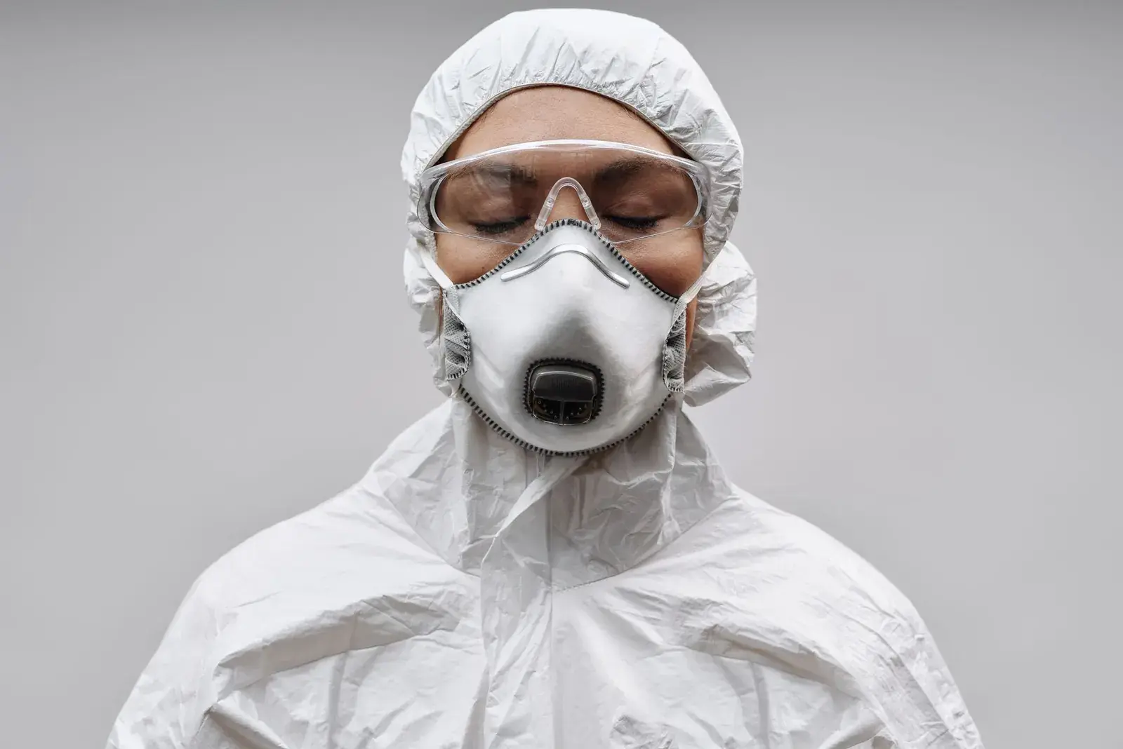 Person in a white protective suit, goggles and respirator