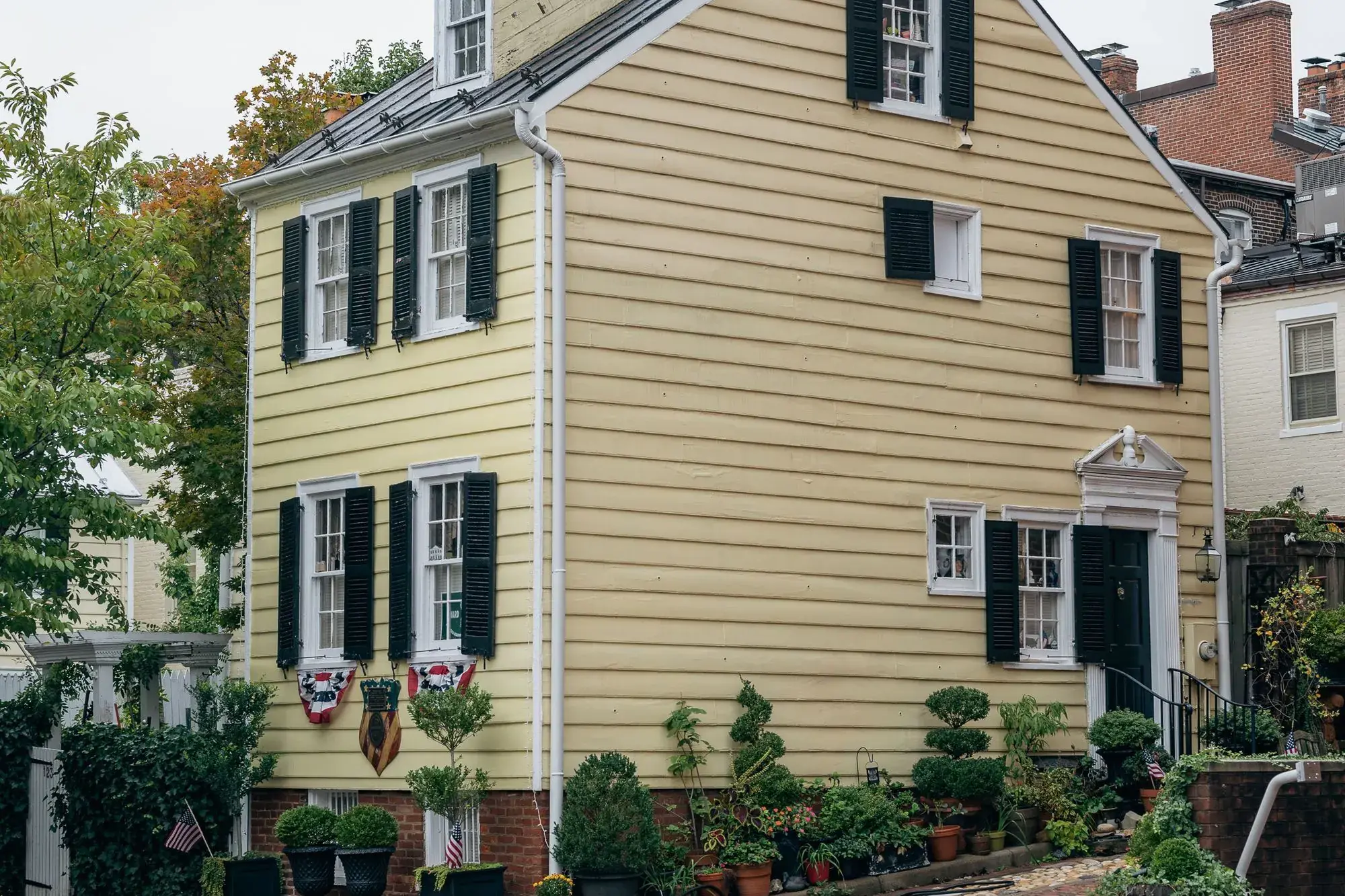 Yellow clapboard house with black shutters