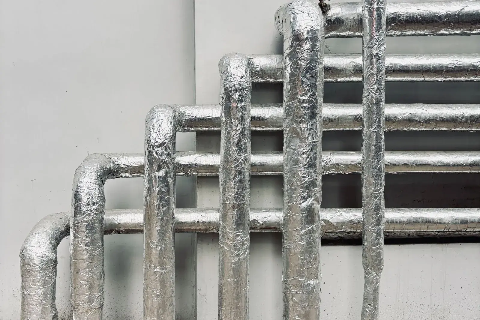 Silver-insulated pipes running along a wall