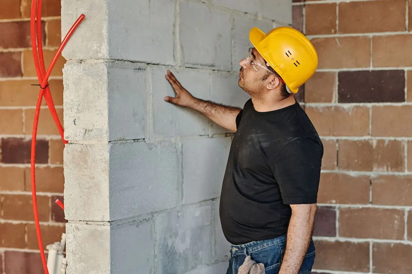 Worker in a hard hat checking a block wall by hand