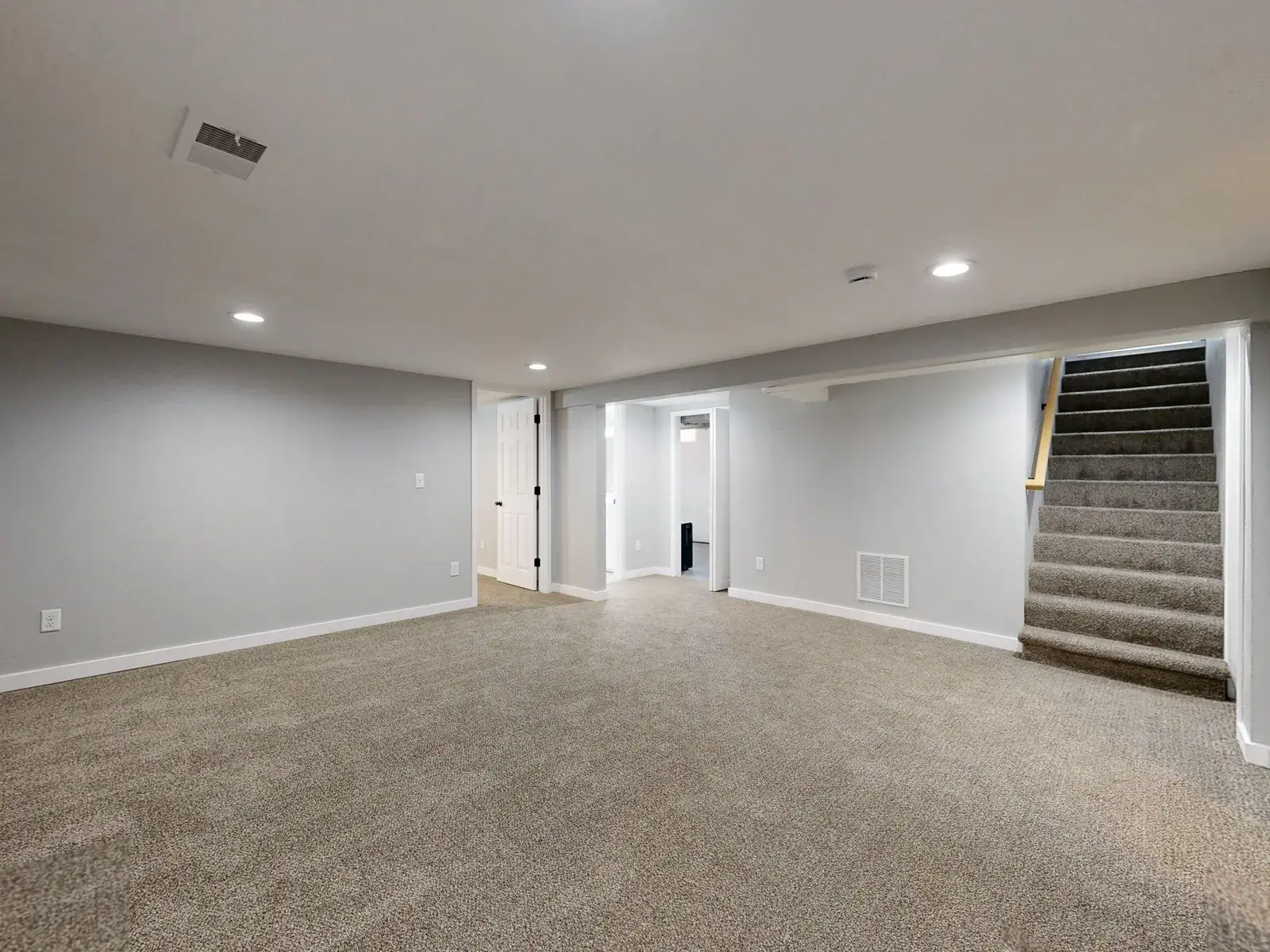 Clean, bright finished basement with carpet and a staircase