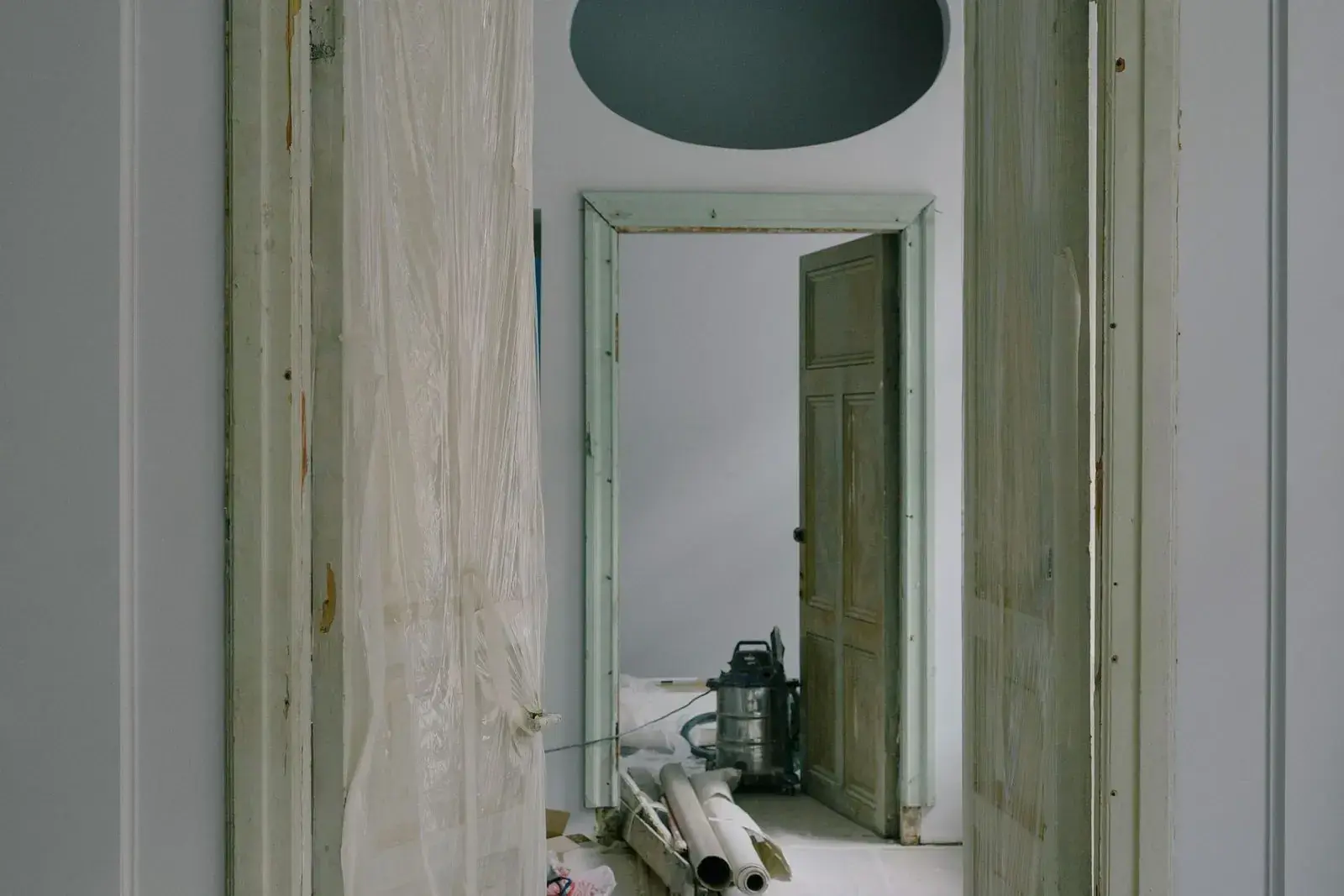 Plastic sheeting hung in a doorway with a vacuum behind it during renovation