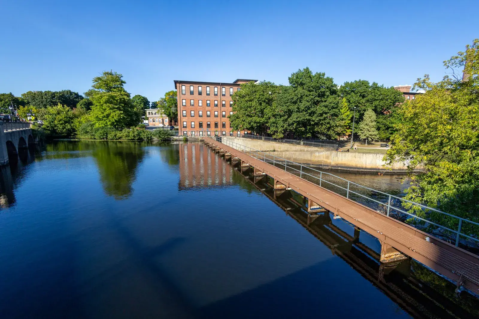 Brick mill building beside a canal with a walkway