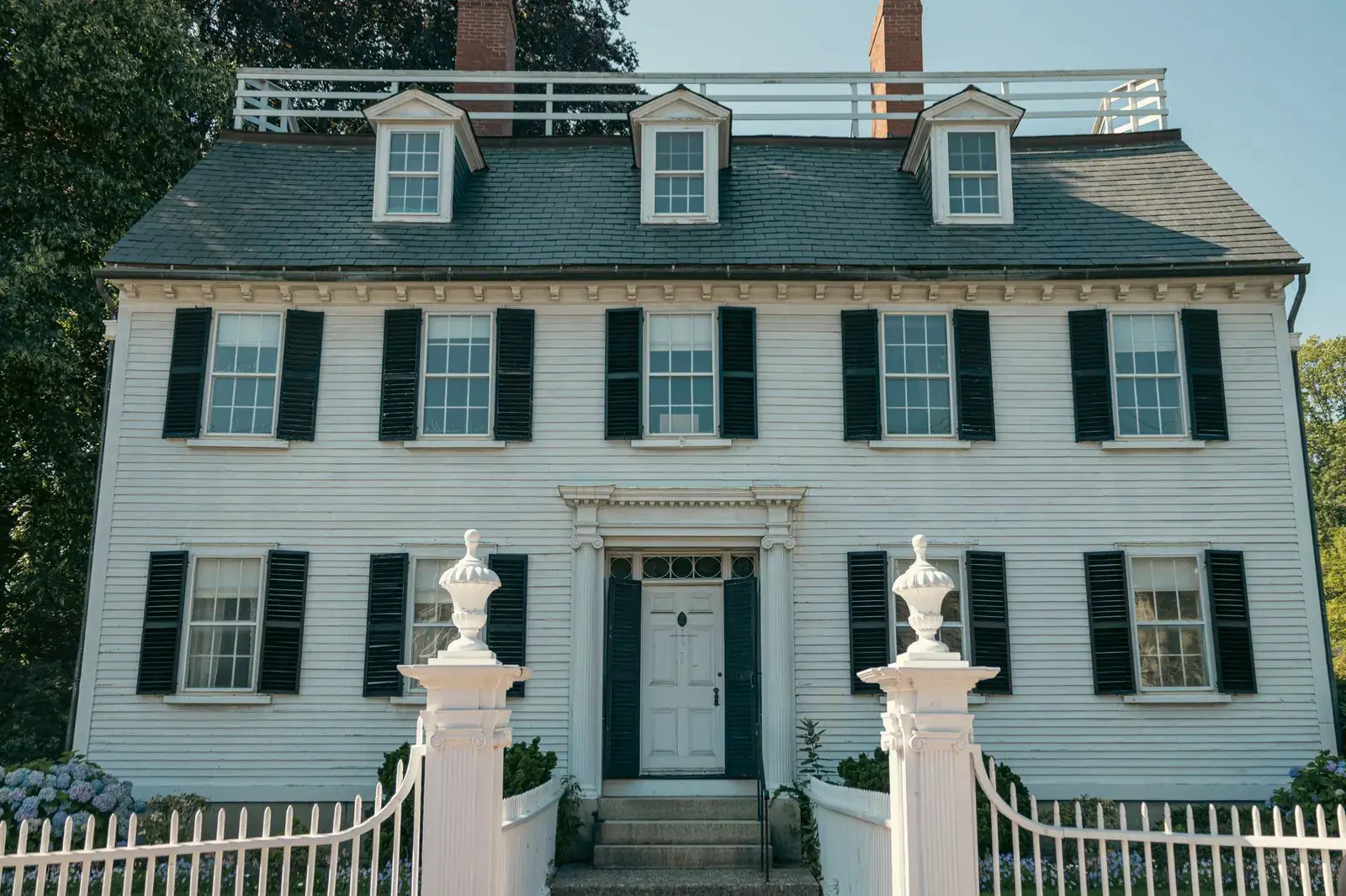 White colonial house with black shutters and a picket fence